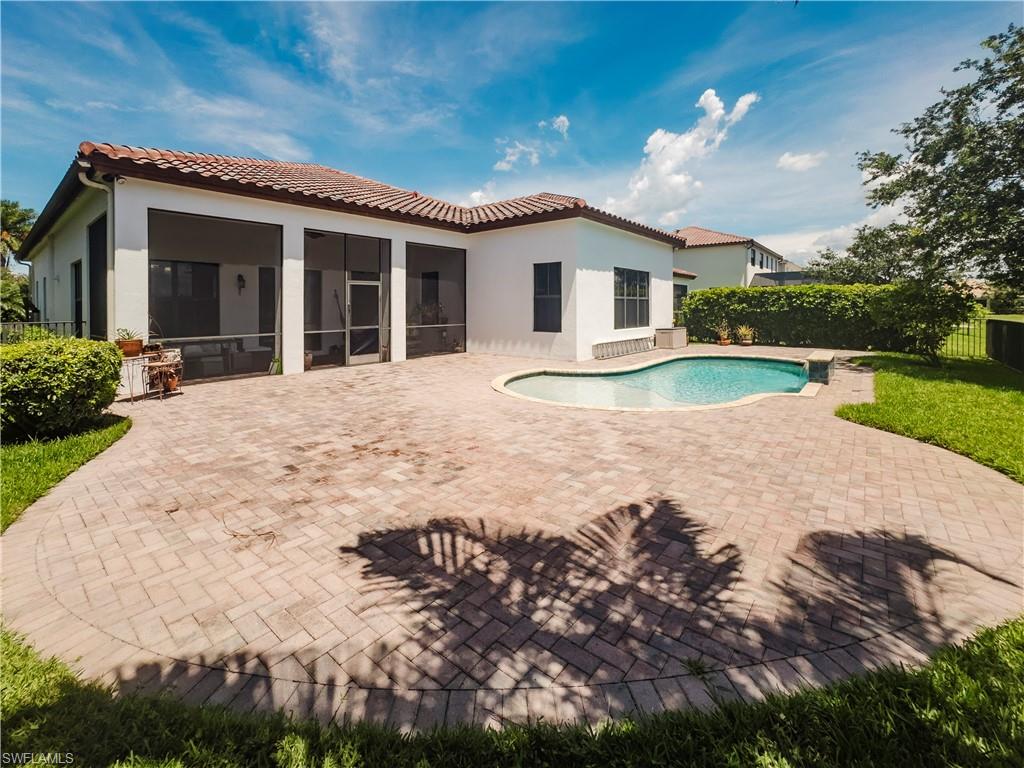 Back of property featuring a patio area, a sunroom, stucco siding, and a tiled roof