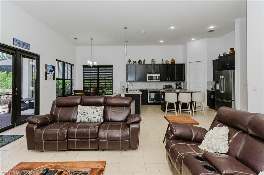 Living area featuring a chandelier, stone tile flooring, a towering ceiling, and recessed lighting