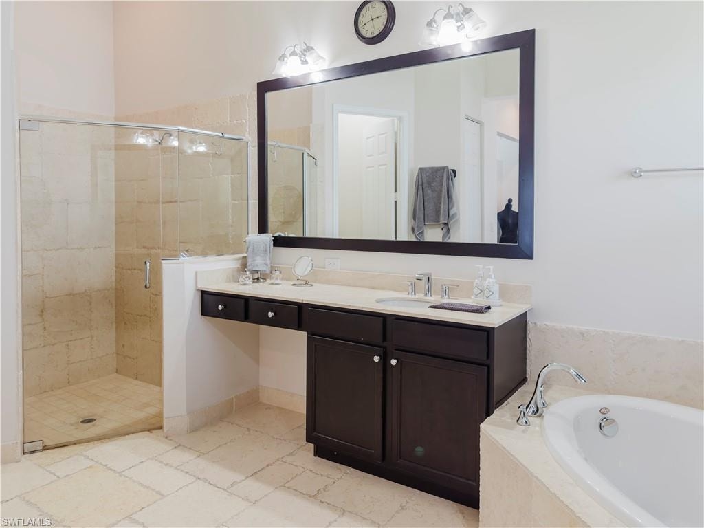 Bathroom featuring a bath, a stall shower, and double vanity