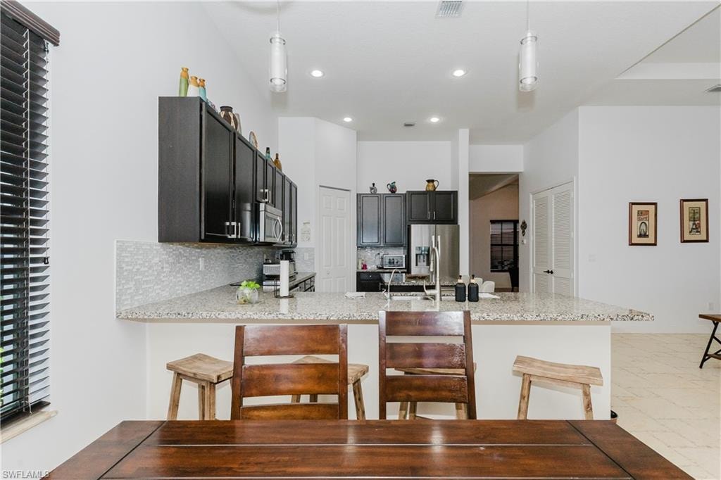 Kitchen featuring a peninsula, recessed lighting, a kitchen bar, pendant lighting, and stainless steel appliances