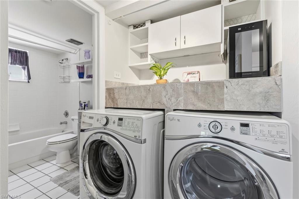 Combined utility and bathroom space featuring white subway tile walls, a built-in bathtub, and a window