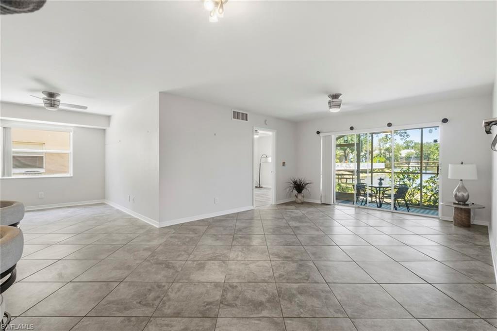 Spacious open-concept living area featuring large format tile flooring and white painted walls