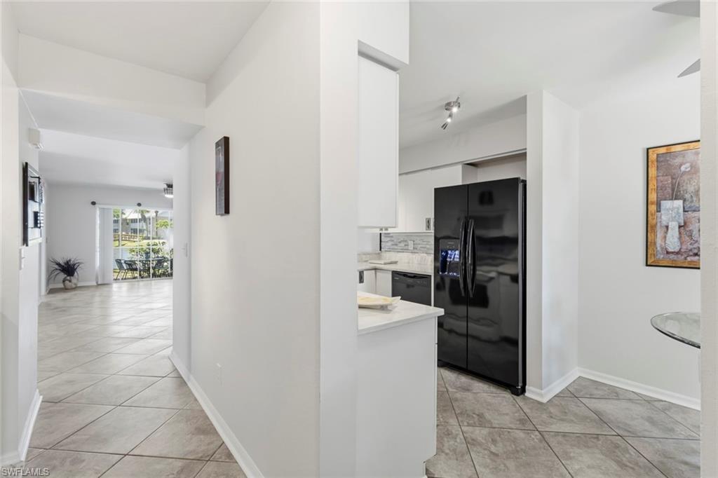 Kitchen featuring a black refrigerator, white cabinetry, track lighting, and a light-toned countertop