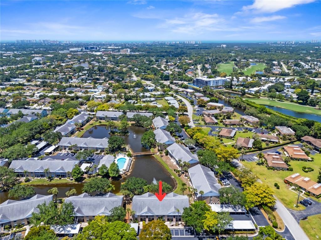 Aerial perspective showcasing a residential community with abundant mature trees, multiple water features, and a community pool