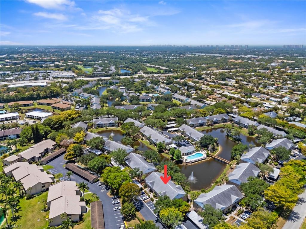Aerial overview of a community featuring multiple residential buildings surrounding a central pond with a fountain