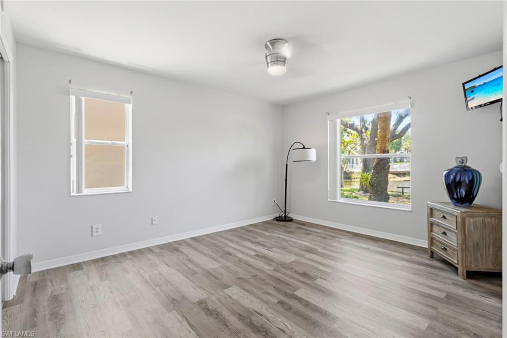 Spacious interior room featuring wood-finish flooring, light gray wall paint, and white trim