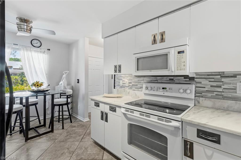Kitchen featuring white cabinetry, stone-finish countertops, and a mosaic tile backsplash