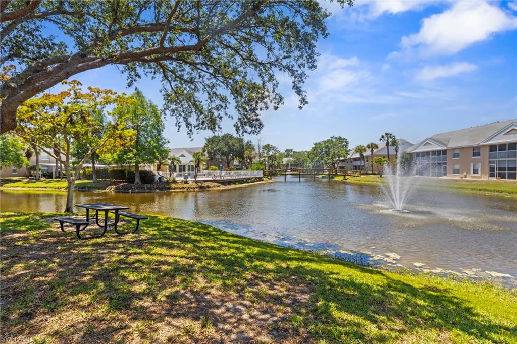 Spacious grounds featuring a prominent pond with a decorative fountain, surrounded by mature trees and manicured lawns