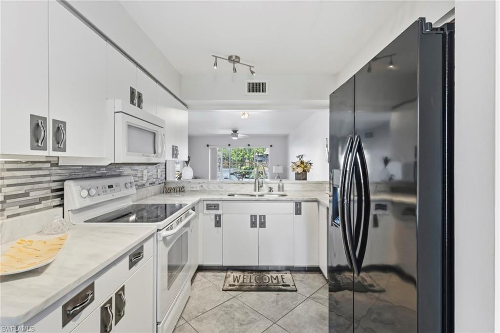 U-shaped kitchen featuring white cabinetry, light-toned countertops, and a tiled backsplash