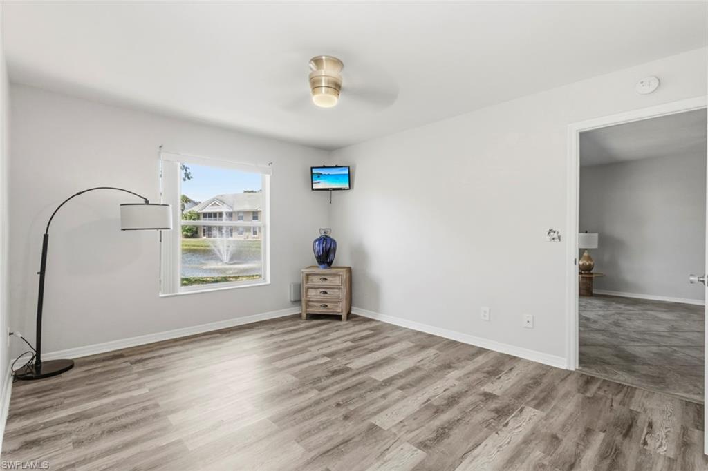 Spacious room featuring wood-finish flooring and a window overlooking a water feature with a fountain