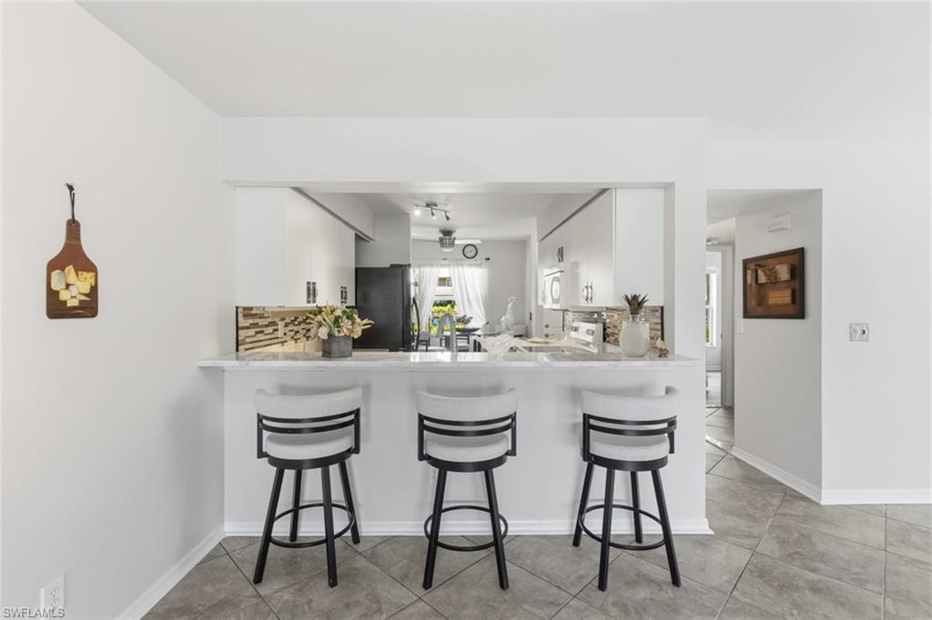 Breakfast bar featuring a light-toned countertop and white base, with a pass-through opening to the kitchen