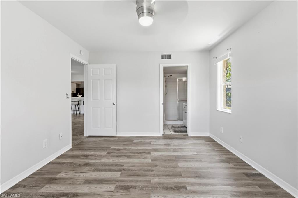 Spacious interior featuring wood-finish flooring, light grey walls, and white trim