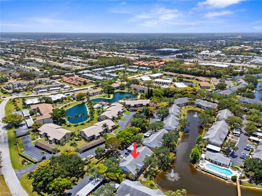 Aerial perspective showcasing a community with multiple residential buildings, surrounded by mature trees and lush landscaping