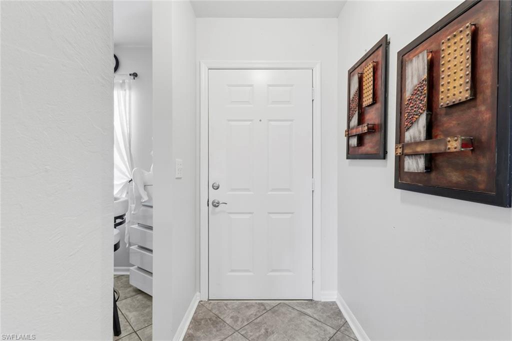 Entryway featuring a paneled door with polished hardware, light gray walls, and diamond-patterned floor tiles