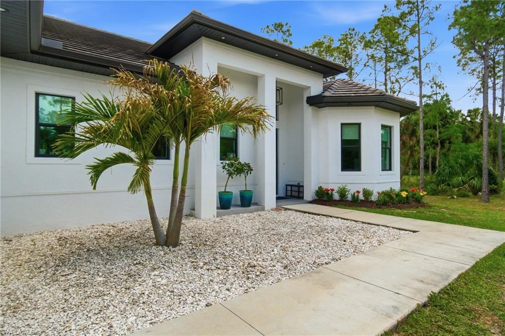 Contemporary architecture featuring a stucco exterior, dark trim, and a prominent entry