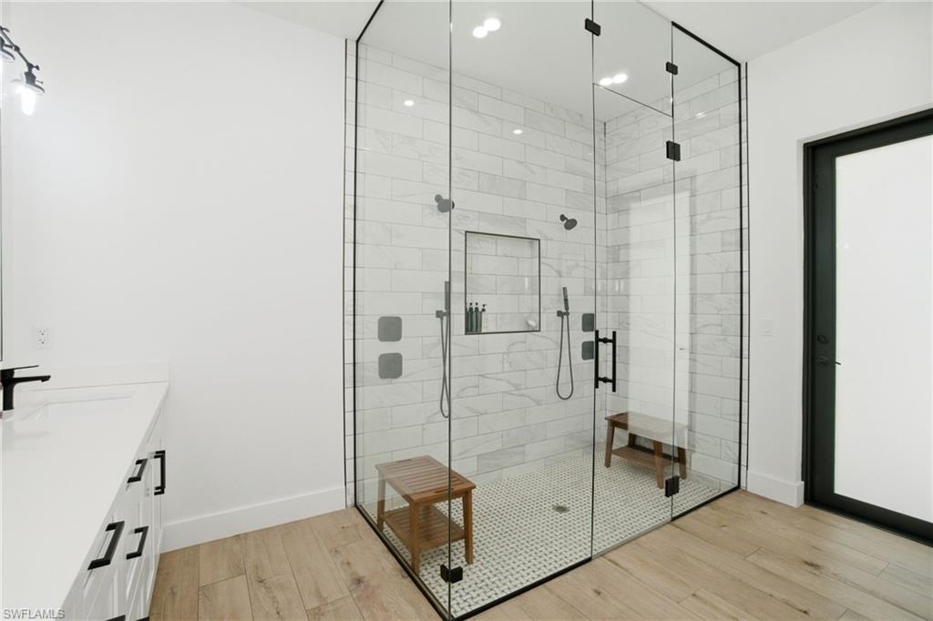 Frameless glass shower enclosure featuring large format subway tile walls, a built-in shower niche, and matte black fixtures