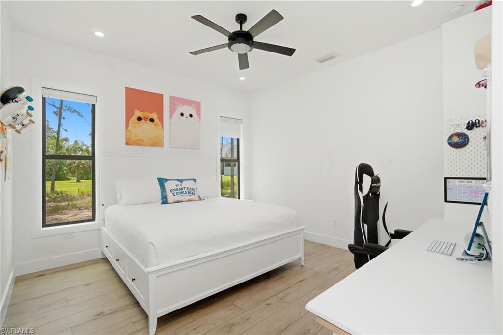 Bright bedroom featuring wood-finish flooring, a contemporary ceiling fan, and recessed lighting