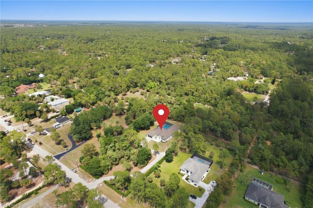 Aerial perspective showcasing a single-story residence with a screened pool enclosure