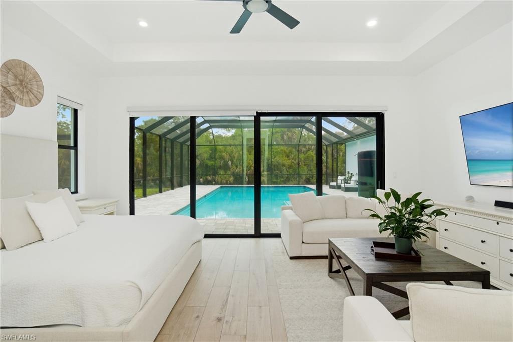 Spacious interior room featuring light wood-finish flooring, a tray ceiling with recessed lighting, and a ceiling fan