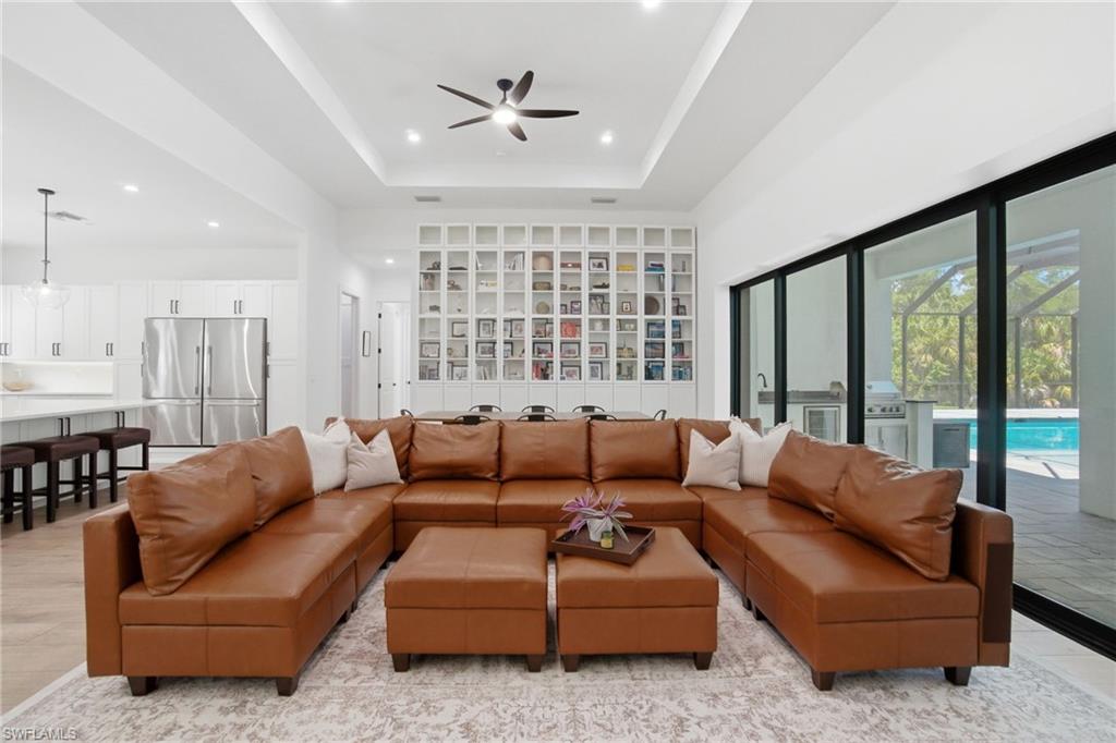 Open-concept living space featuring a tray ceiling with a ceiling fan