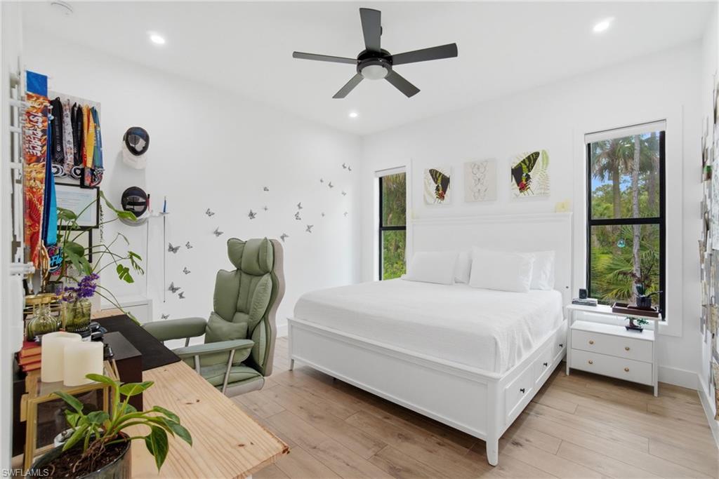 Hardwood-finish flooring featuring recessed lighting, a ceiling fan, and multiple large windows with black frames