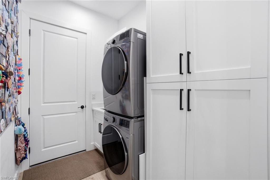 Laundry area featuring white shaker-style cabinetry with matte black hardware