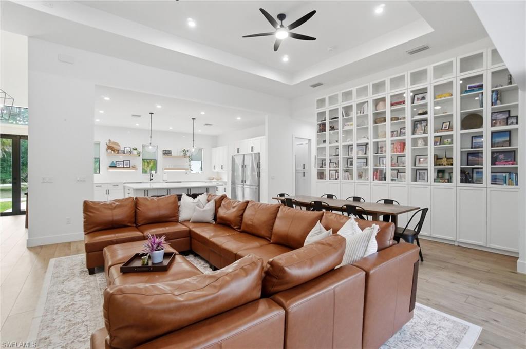 Expansive living area with wood-finish flooring and a tray ceiling featuring a ceiling fan