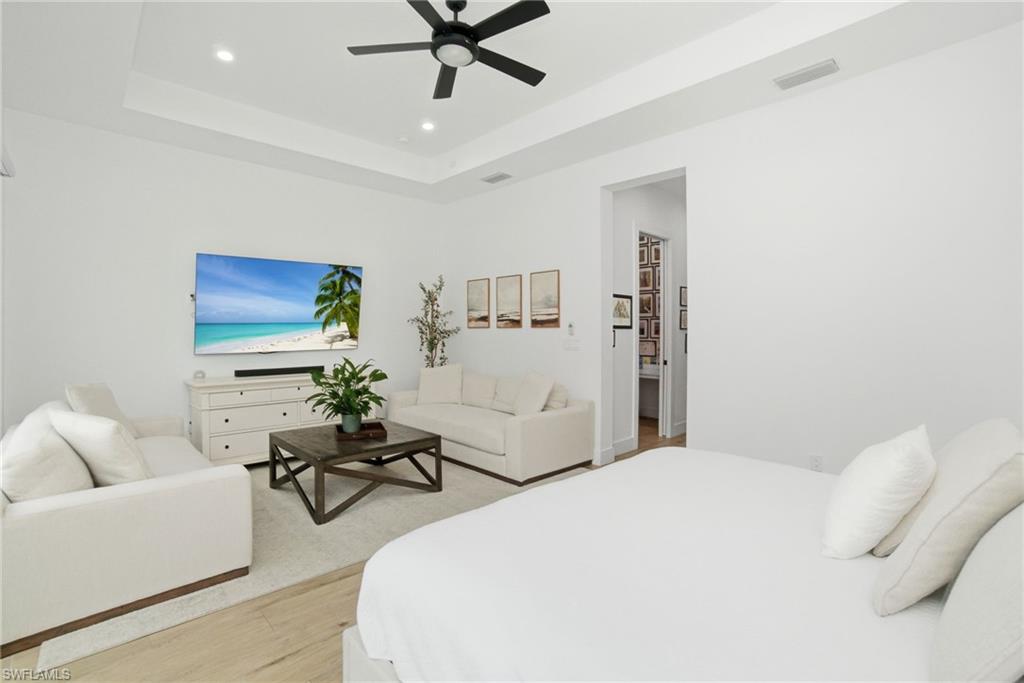 Spacious room featuring a tray ceiling with recessed lighting and a black ceiling fan