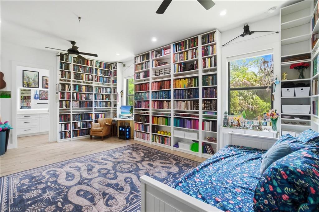 Room featuring extensive built-in shelving, wood-finish flooring, and a ceiling fan