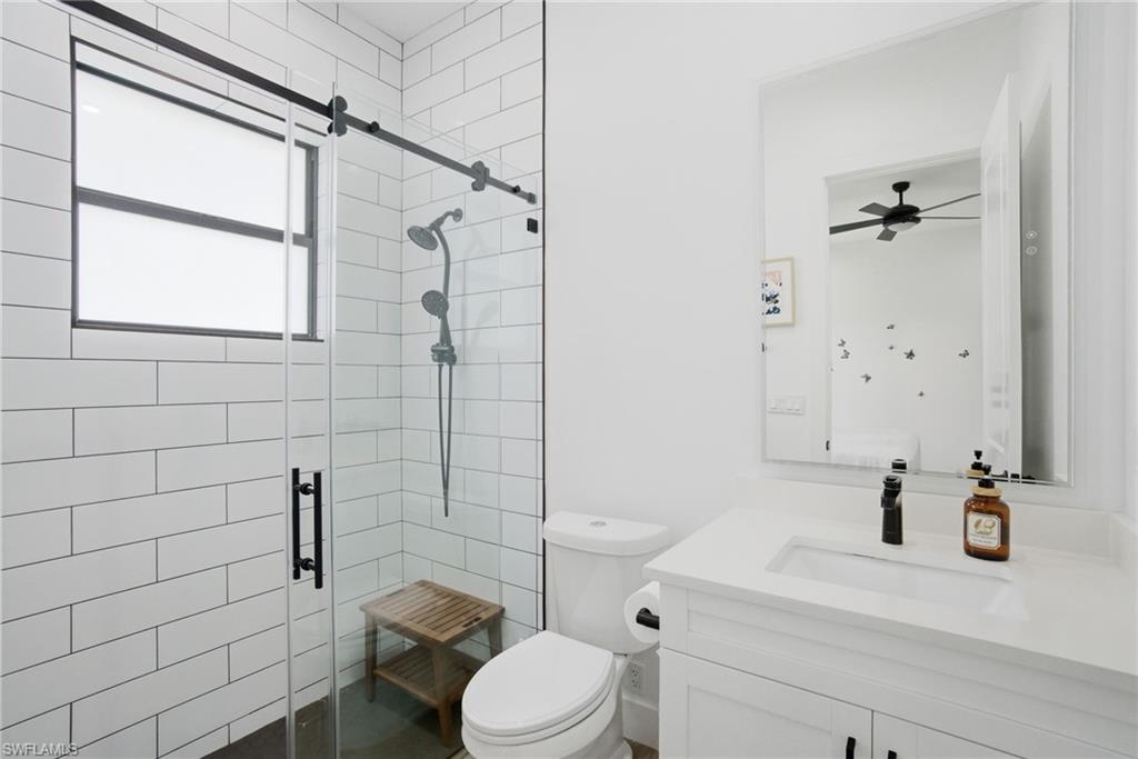 White subway tile shower with a clear glass enclosure, matte black fixtures, and a window