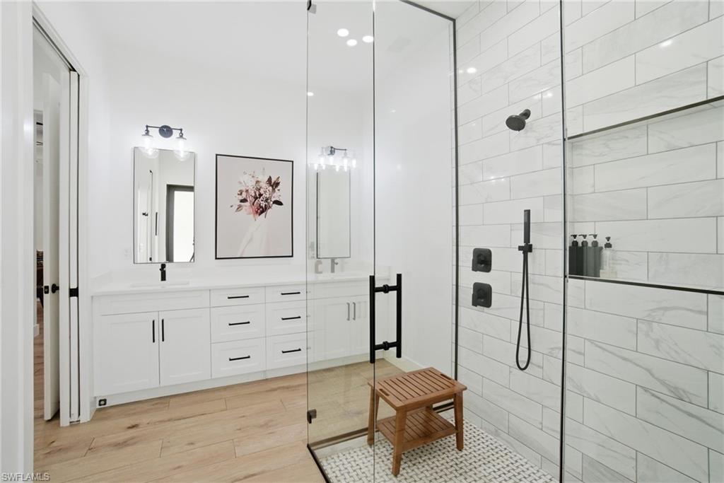 Spacious bathroom featuring a glass-enclosed shower with matte black fixtures, a built-in shower niche, and white subway tile