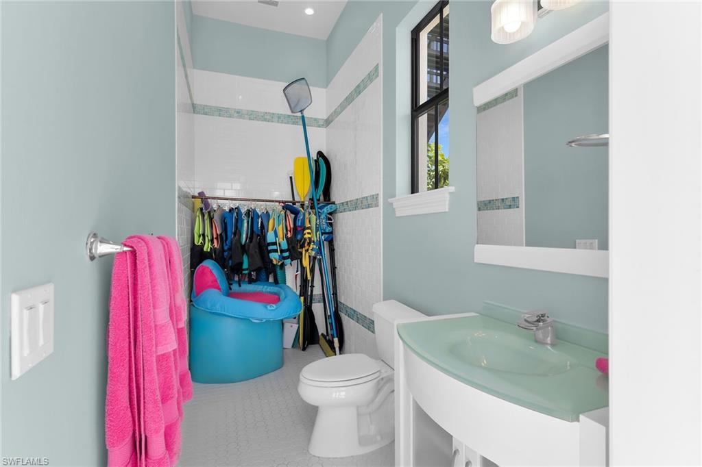Bathroom featuring a frosted glass vessel sink, white vanity, and a window with architectural grilles