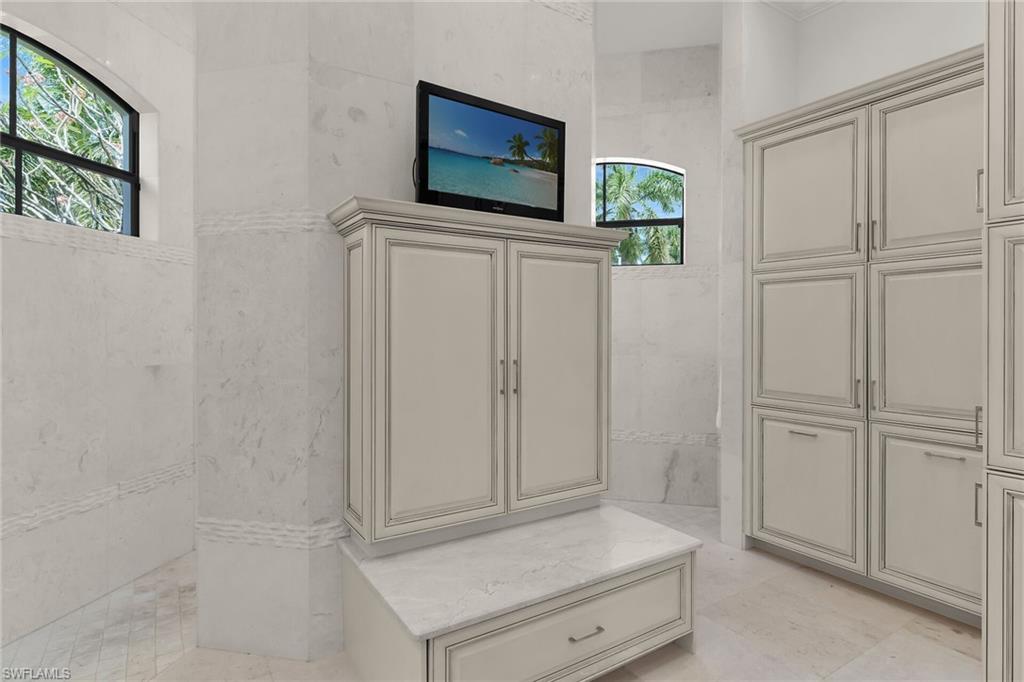 Light-colored cabinetry with brushed nickel hardware, accented by arched windows with black frames