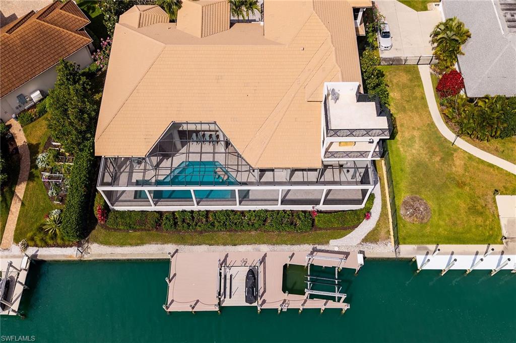 Waterfront property featuring a screened-in pool enclosure, private dock, and boat lift