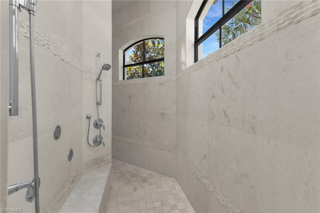 Spacious shower with large format wall tiles, a built-in bench, and multiple shower heads