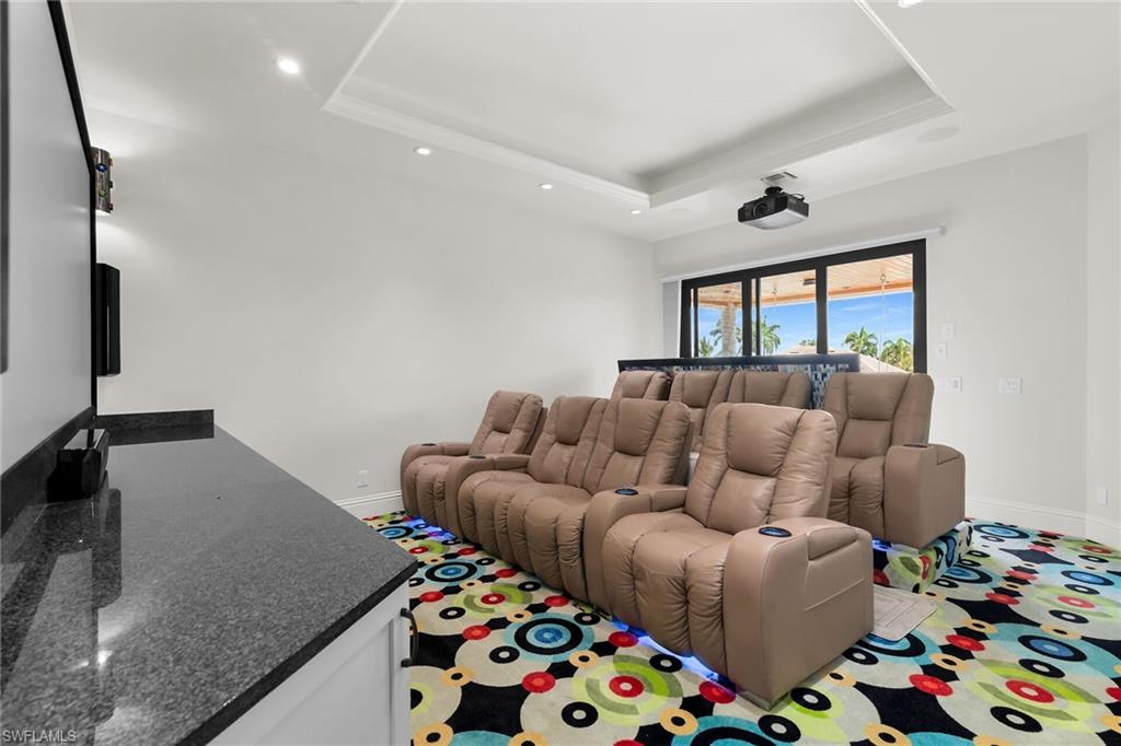 Dedicated media room featuring tiered seating, a large projection screen, and a ceiling-mounted projector