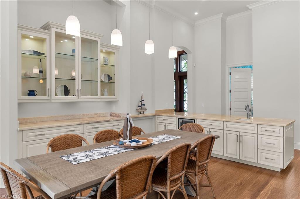 Dining area featuring wood-finish flooring and a built-in wet bar with a compact refrigerator