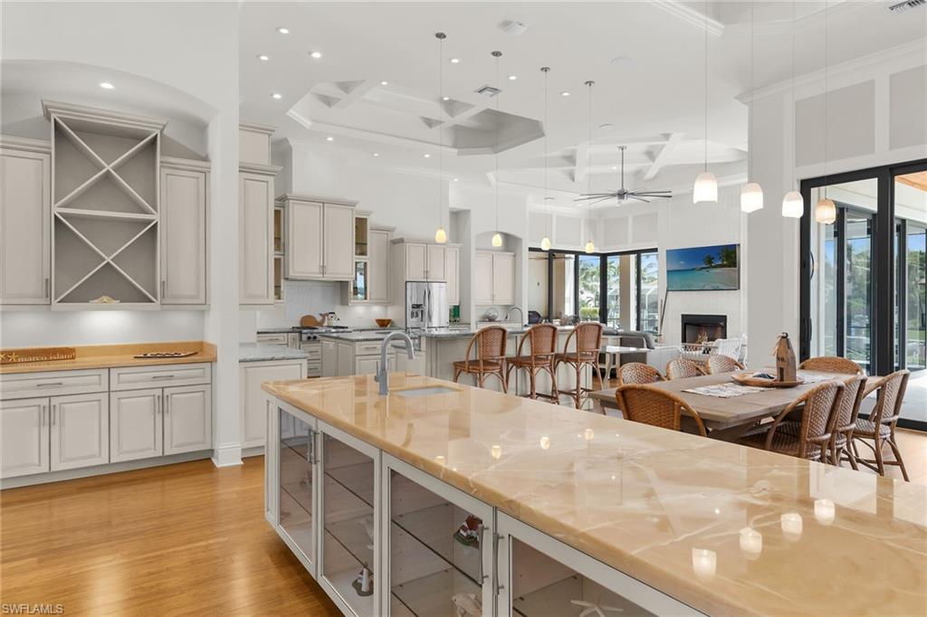 Open-concept living space featuring a large kitchen island with a polished countertop, light-toned cabinetry, and hardwood flooring