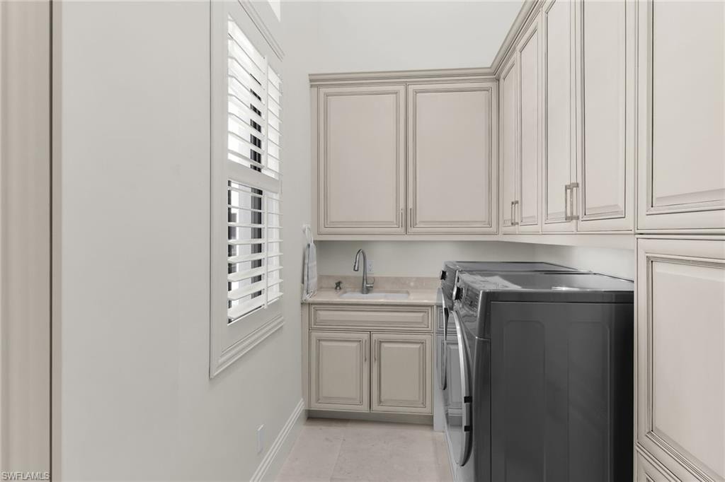 Laundry room featuring built-in cabinetry, light-toned countertops, and a utility sink