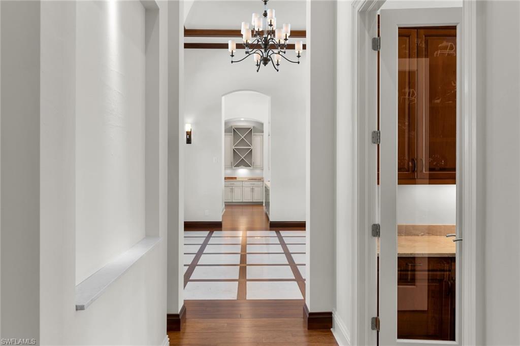 Hallway featuring wood-finish flooring with square tile inlays, arched doorways, and a chandelier