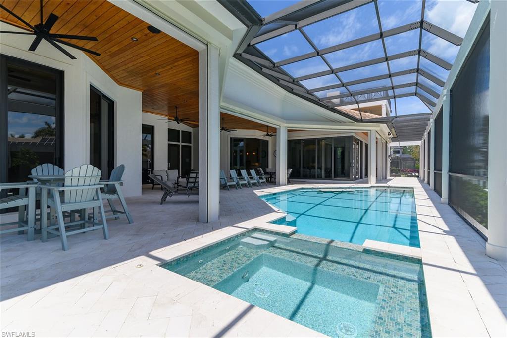 Screened lanai featuring a swimming pool, integrated spa, and extensive white tile decking