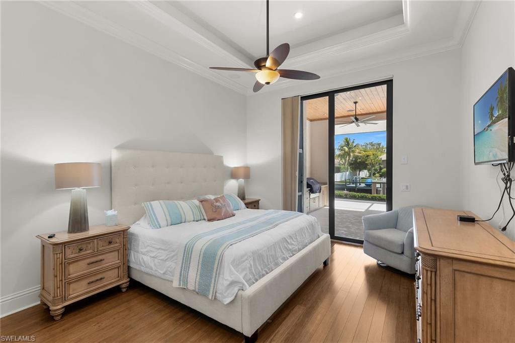 Tray ceiling with crown molding, wood-finish flooring, and direct access to an outdoor living area