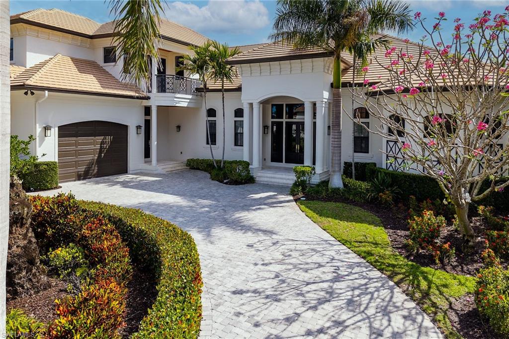Stucco exterior with a tiled roof, arched entryways, and a paver driveway