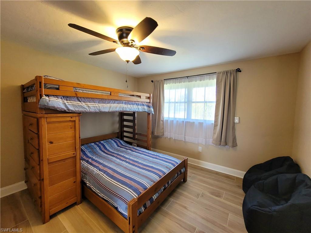Bedroom featuring wood-finish flooring and a multi-pane window with neutral drapes