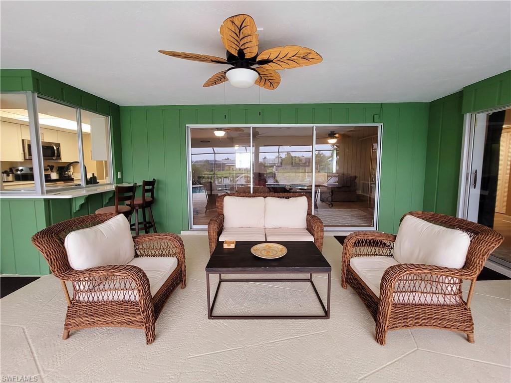 Expansive screened lanai featuring a tropical-inspired ceiling fan and a pass-through window to the interior kitchen