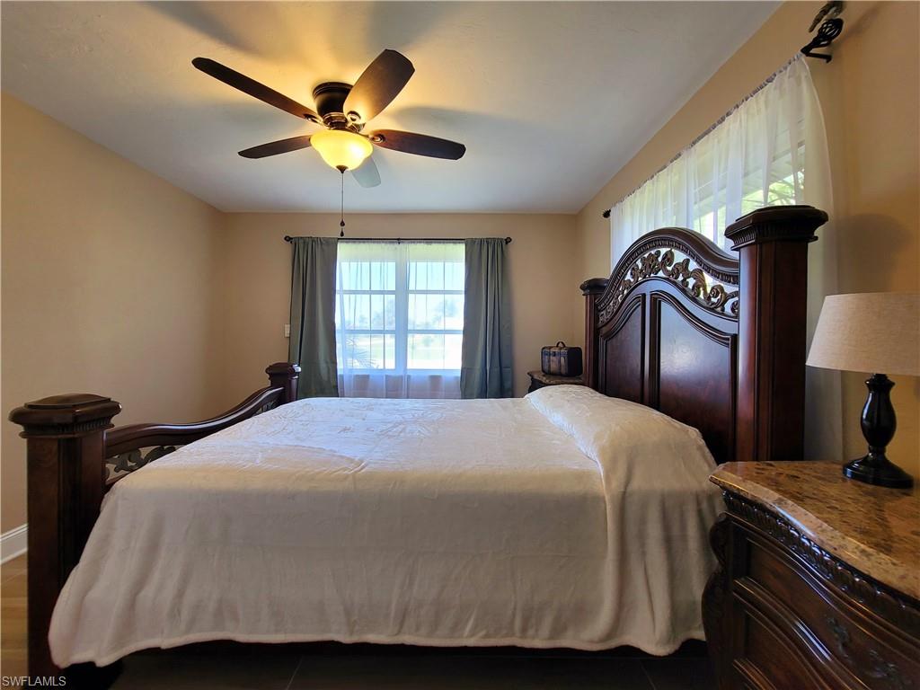 Bedroom featuring a ceiling fan with integrated lighting, a window with horizontal muntins and drapes, and neutral wall paint