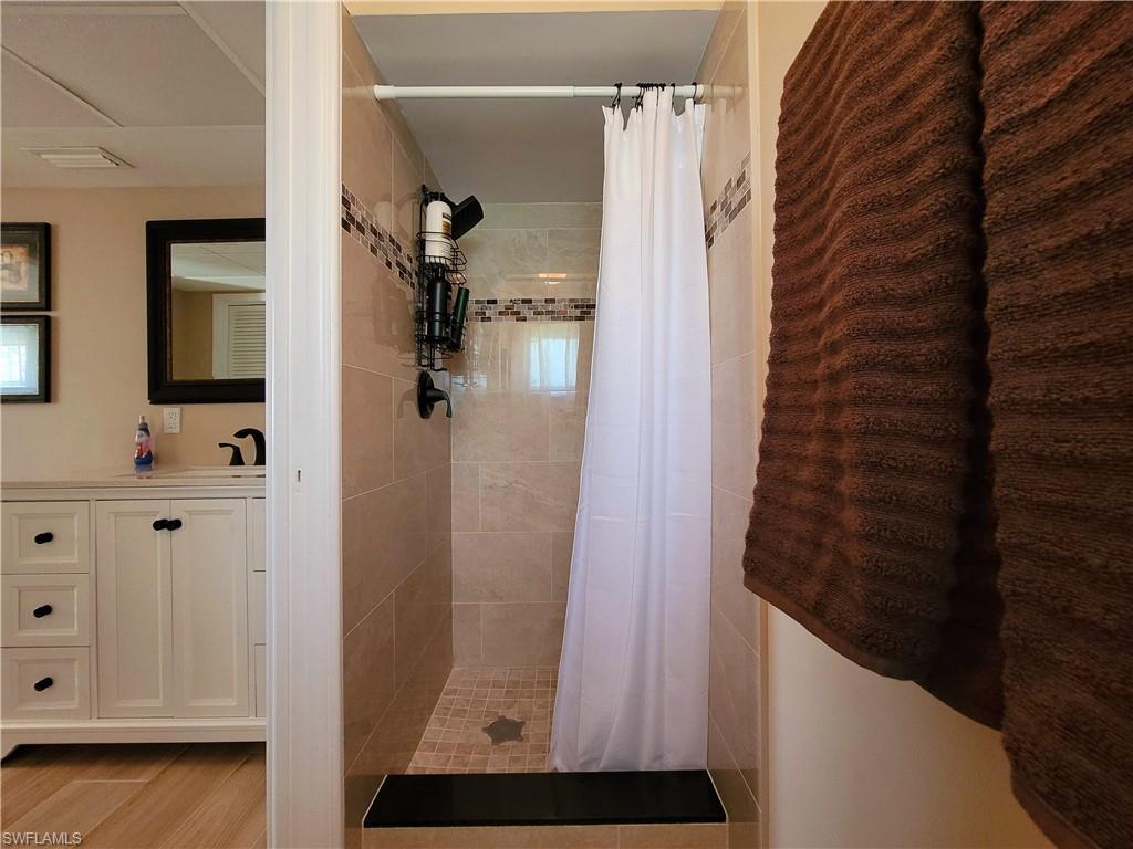 Tiled shower stall with a black threshold and decorative mosaic accent band