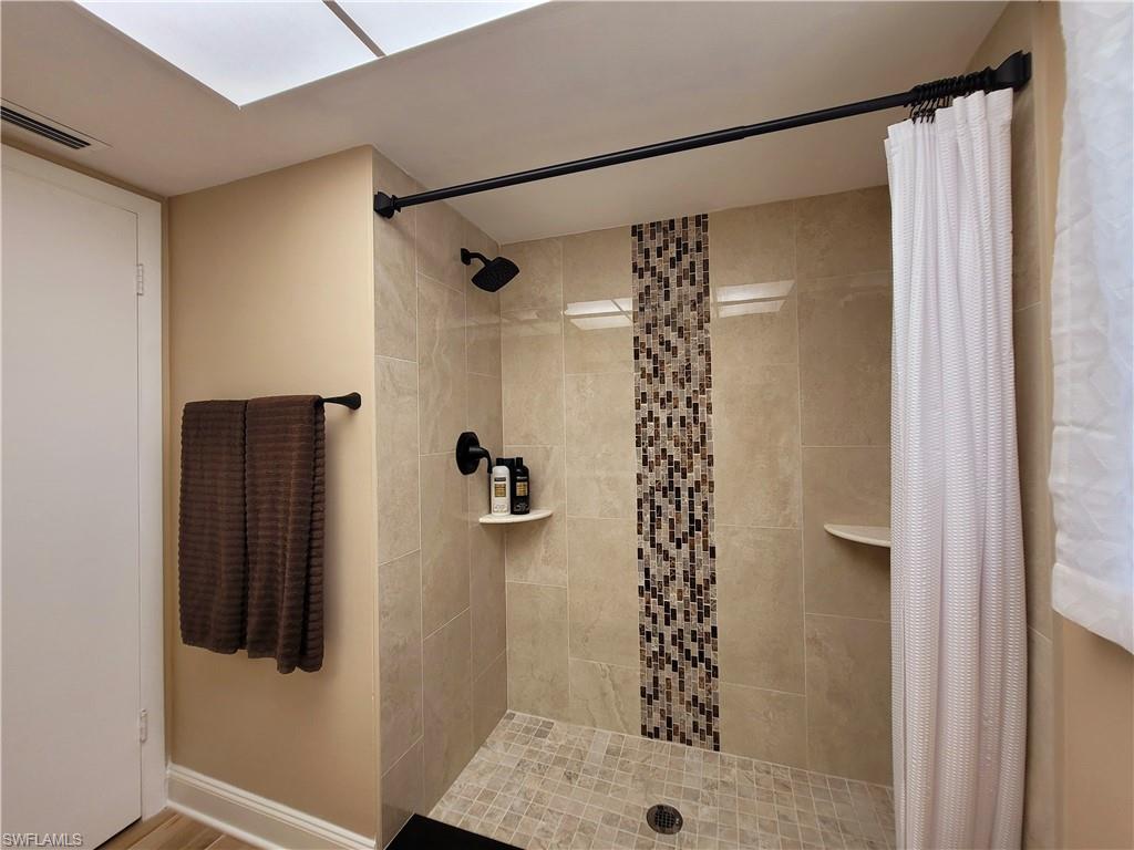 Shower with large format wall tiling, mosaic tile accent, and a tiled shower pan
