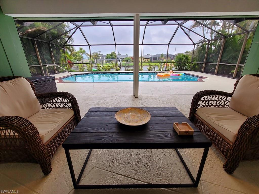 Screened lanai featuring a swimming pool, concrete decking, and waterfront access