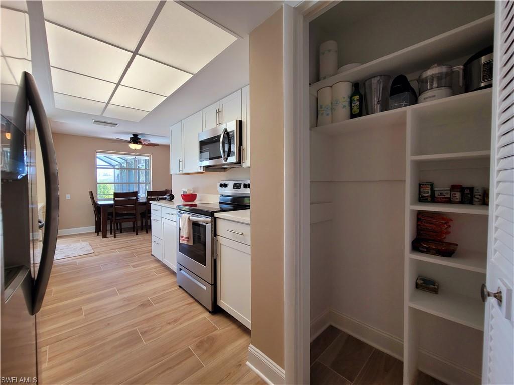 Kitchen featuring white cabinetry with silver-tone hardware, stainless steel appliances, and a pantry with built-in shelving